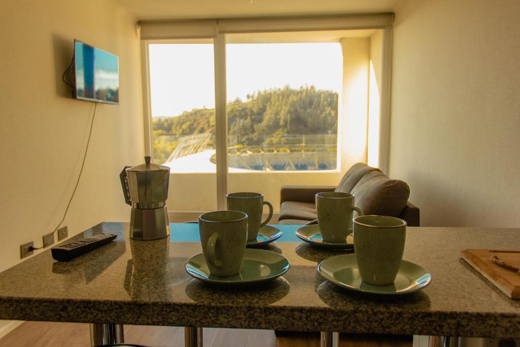 a table with four coffee cups on it with a window at Nuevo Depto 3 camas, vista al estadio y estacionamiento gratis in Concepción