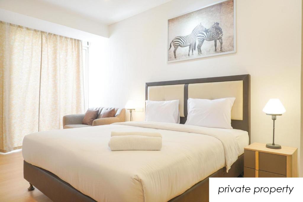a bedroom with a large white bed with a picture of zebras at Warm Aston Bellevue HOTEL Apartment - SMART TV in Jakarta
