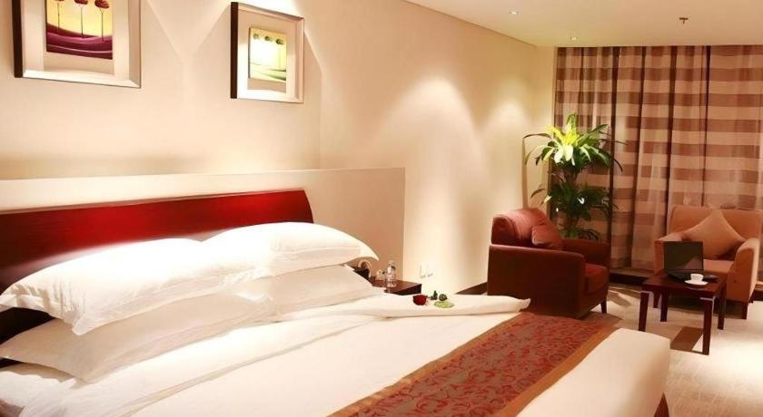 ein Schlafzimmer mit einem großen weißen Bett und einem Stuhl in der Unterkunft Best Western Tianjin Juchuan Hotel in Binhai