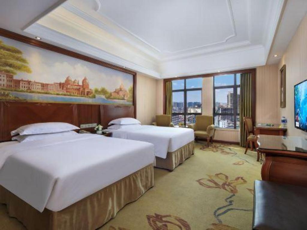 a hotel room with two beds and a flat screen tv at Vienna International Hotel Nanning Railway Station Mingxiu Road Metro Station in Nanning