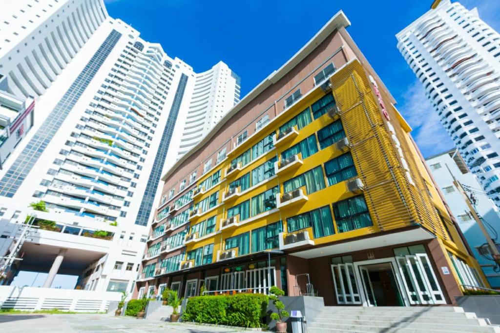 a yellow building in front of tall buildings at Neo Hotel in Jomtien Beach