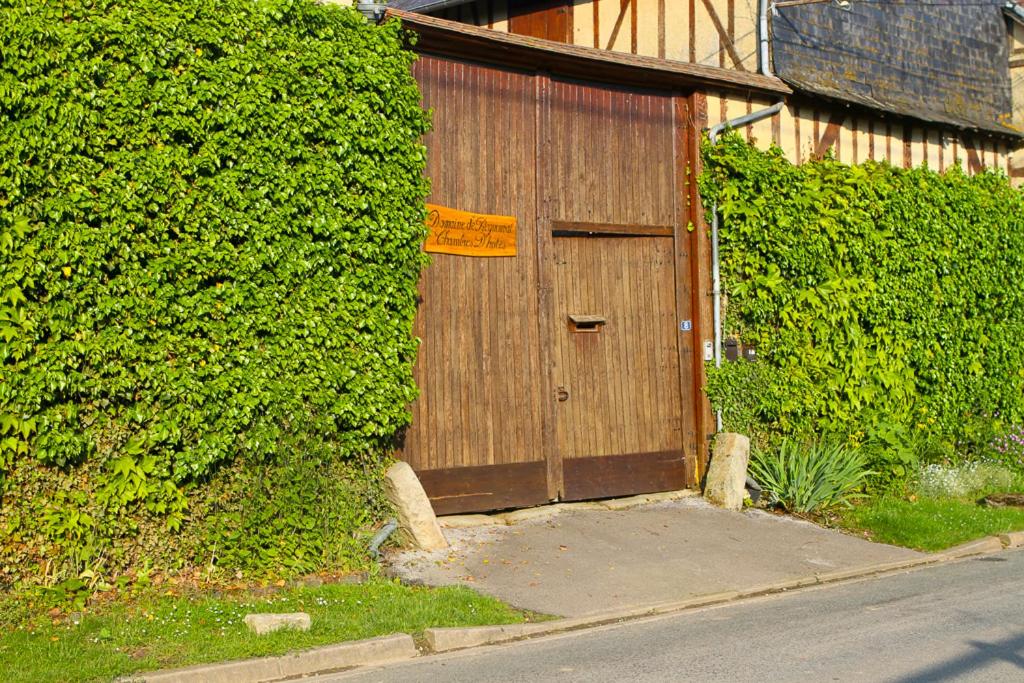 una puerta de madera al lado de un arbusto en Domaine de Regnonval, en Blicourt