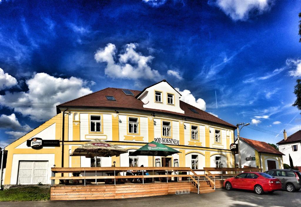 ein gelbes Gebäude mit Sonnenschirmen davor in der Unterkunft Hotel Pod Kokšínem in Spálené Poříčí