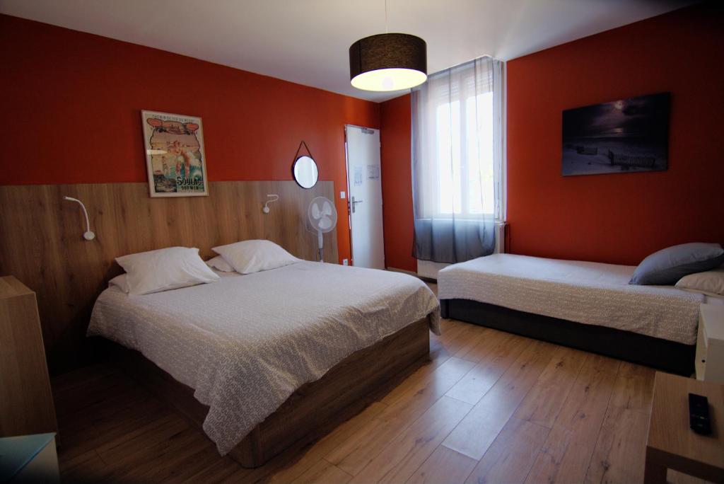 a bedroom with two beds and orange walls at Hôtel L'Arbousier in Soulac-sur-Mer