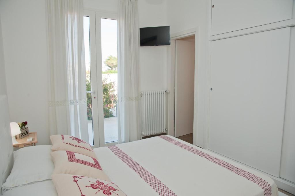 a white bedroom with a bed and a window at LI CURTI B&B in Melissano