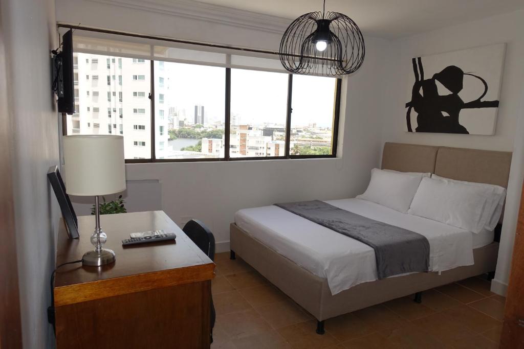 um quarto com uma cama, uma escrivaninha e uma janela em Cabrero Beach 1008 em Cartagena de Indias