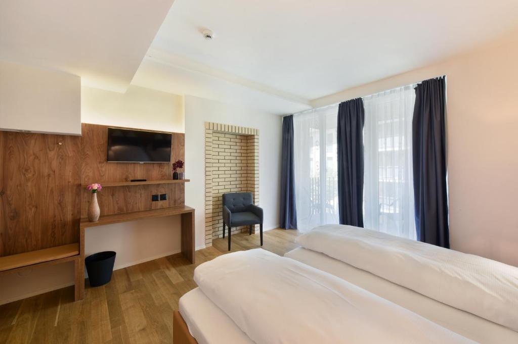 a hotel room with two beds and a television at Hotel Central in Engelberg