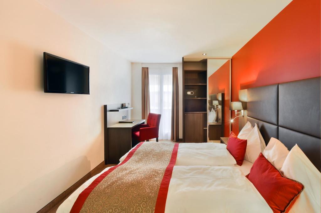 a hotel room with a large bed with red pillows at Hotel Central in Engelberg