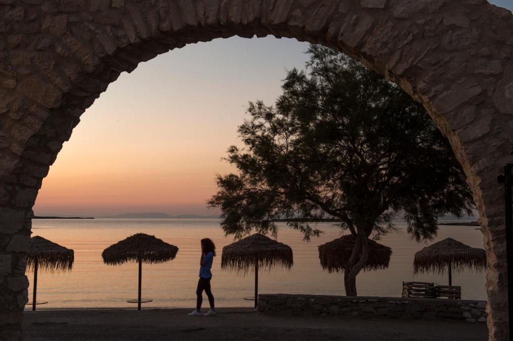 a woman walking through an archway looking out at the water at Contaratos Beach Hotel in Naousa