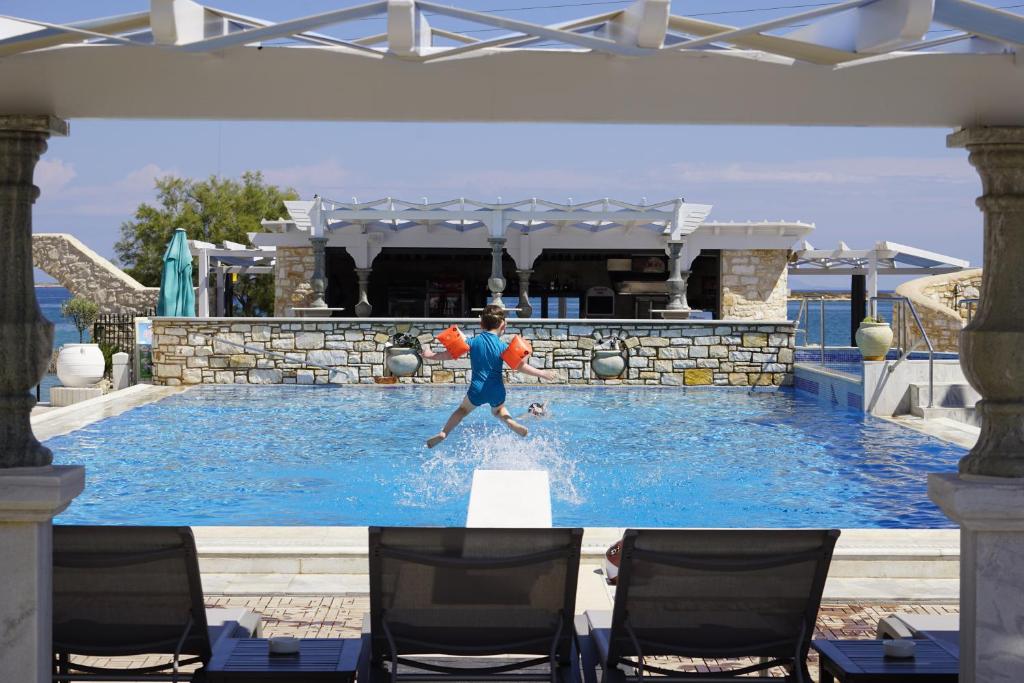 a man is in the water in a swimming pool at Contaratos Beach Hotel in Naousa