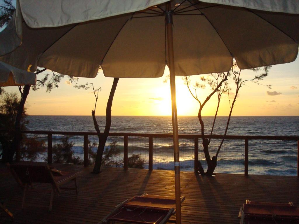 an umbrella and chairs on a deck with the ocean at Cala Dei Mori in Livorno