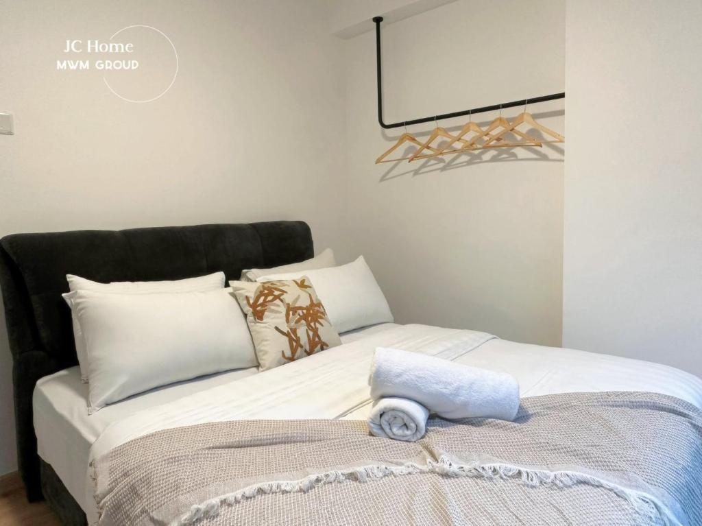 a bed with white pillows and a towel on it at Black White Sea Salt Theme Midas Seri Alam in Masai