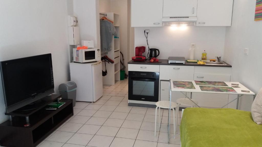 a living room with a kitchen with a tv and a table at Studio dans la Villa "Litita" à Nice in Nice