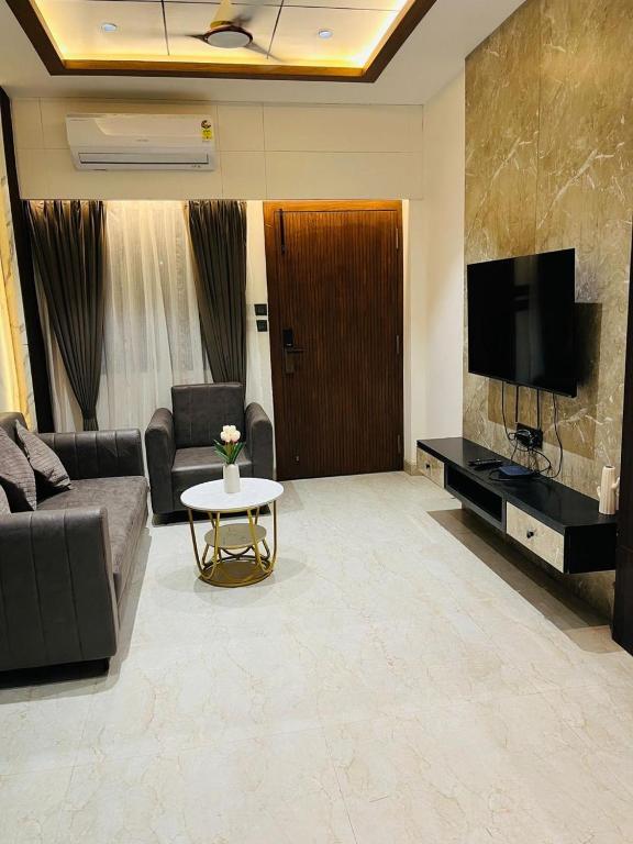 a living room with a couch and a tv and a table at The Divine Villa! in Indore