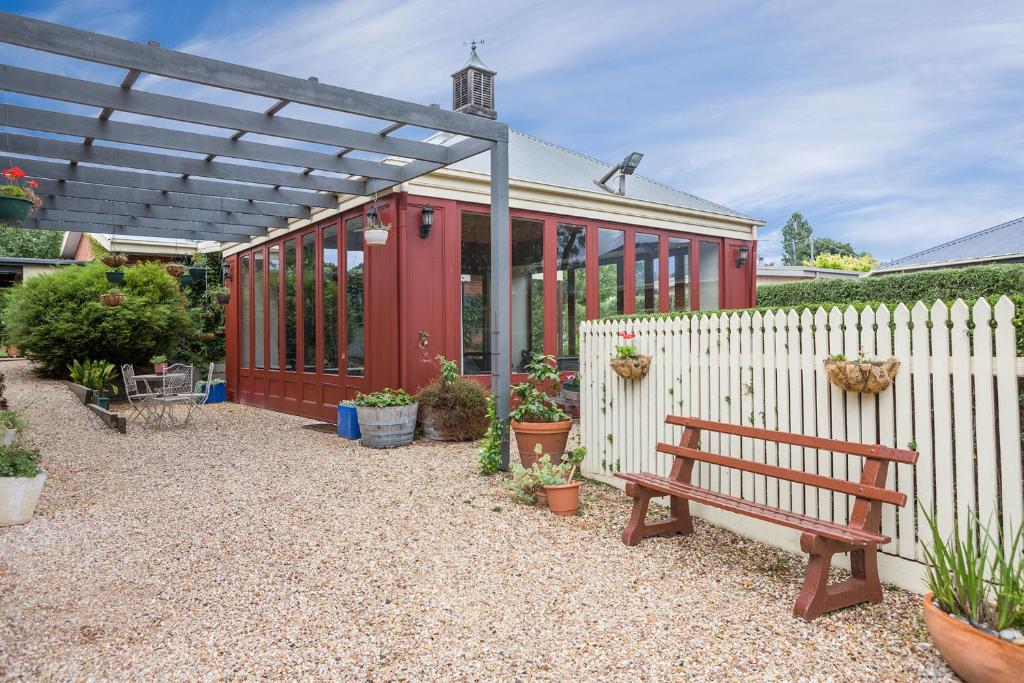 ein rotes Haus mit einer Bank und einem Zaun in der Unterkunft Lancefield Guest House in Lance Field