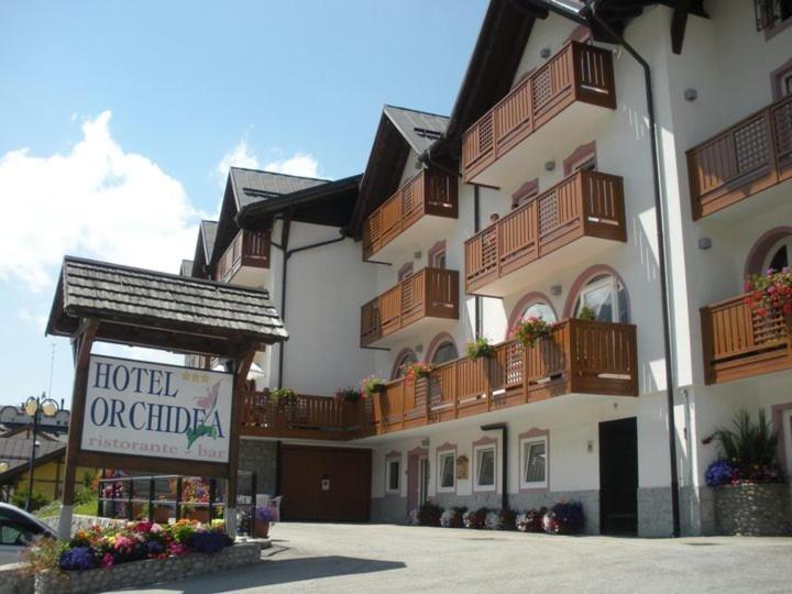 un bâtiment d'hôtel ou d'appartement avec un panneau devant lui dans l'établissement Hotel Orchidea, à Passo del Tonale