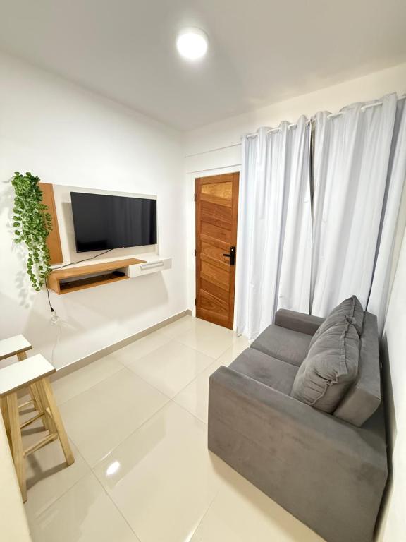 a living room with a couch and a flat screen tv at Apartamento Praia Jacaraípe in Serra