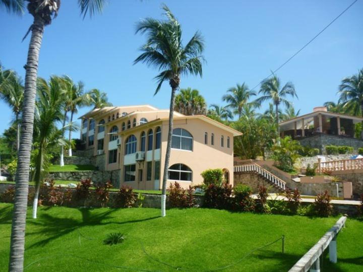 een groot huis met palmbomen en een groene tuin bij Hotel Barlovento in Puerto Escondido