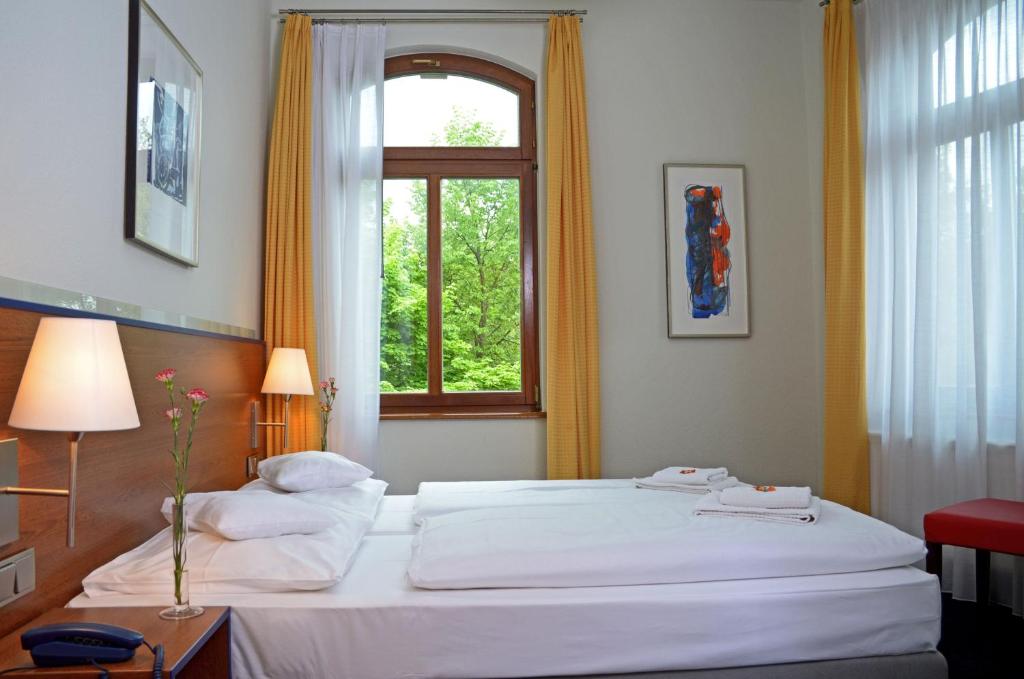 a bedroom with a large white bed with a window at Hotel & Apartments Fürstenhof am Bauhaus in Weimar