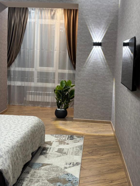 a bedroom with a bed and a window with a plant at VIP кв 10 мкр in Oral