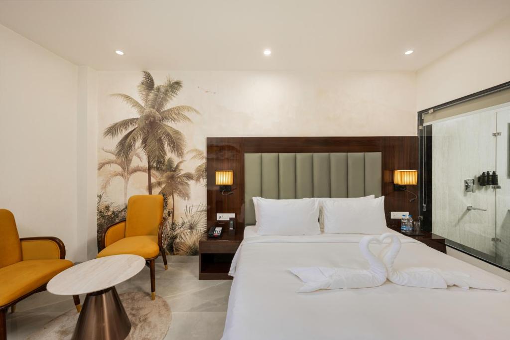 齐拉克普尔AVA Hotel Chandigarh Zirakpur的卧室里有一张白色的大床和两把橙色的椅子