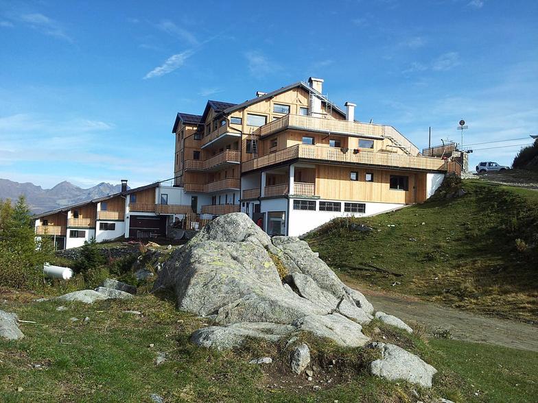 Un edificio in cima a una collina con una roccia di Rifugio Orso Bruno a Commezzadura