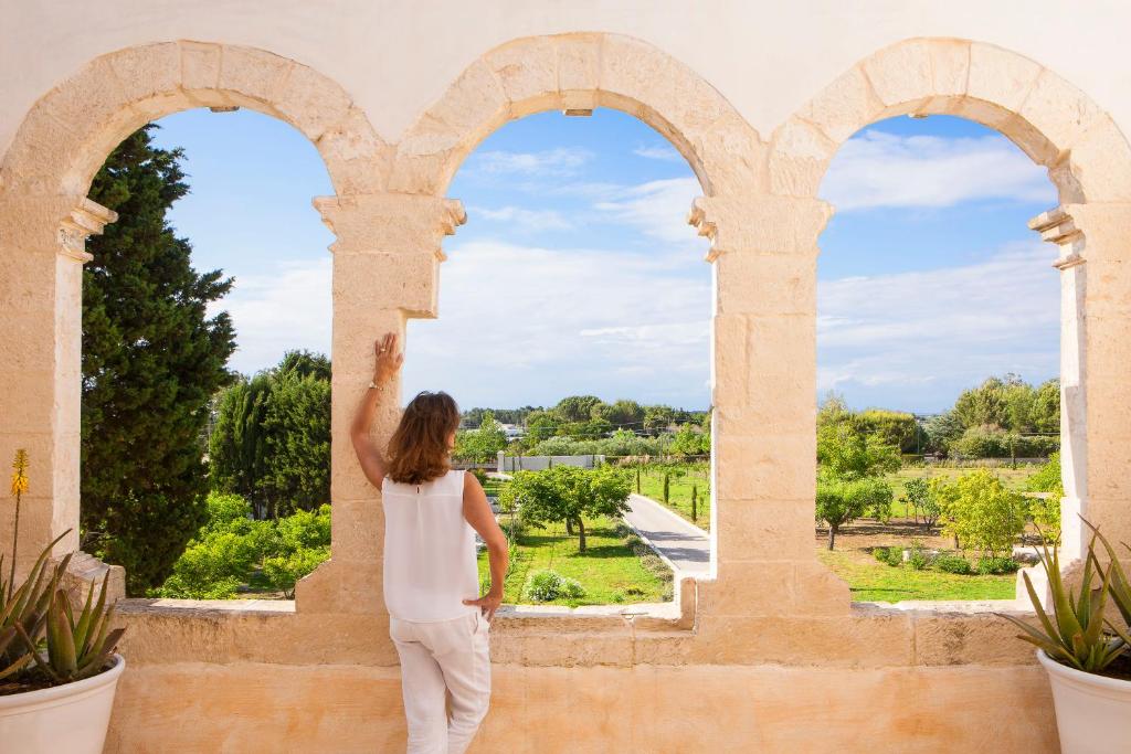 a woman looking out of an archway in a castle at Critabianca - Masseria in Salento in Cutrofiano
