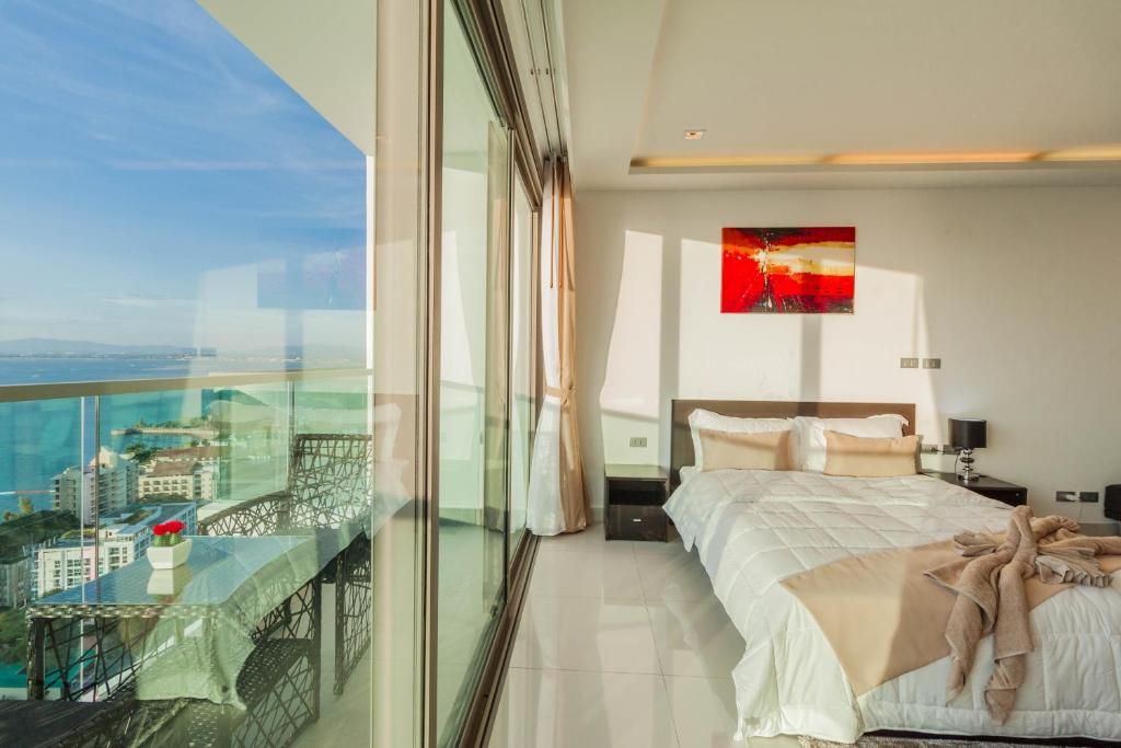 a bedroom with a bed and a balcony with a view at Wongamat Tower by Pattaya Sunny Rentals in North Pattaya