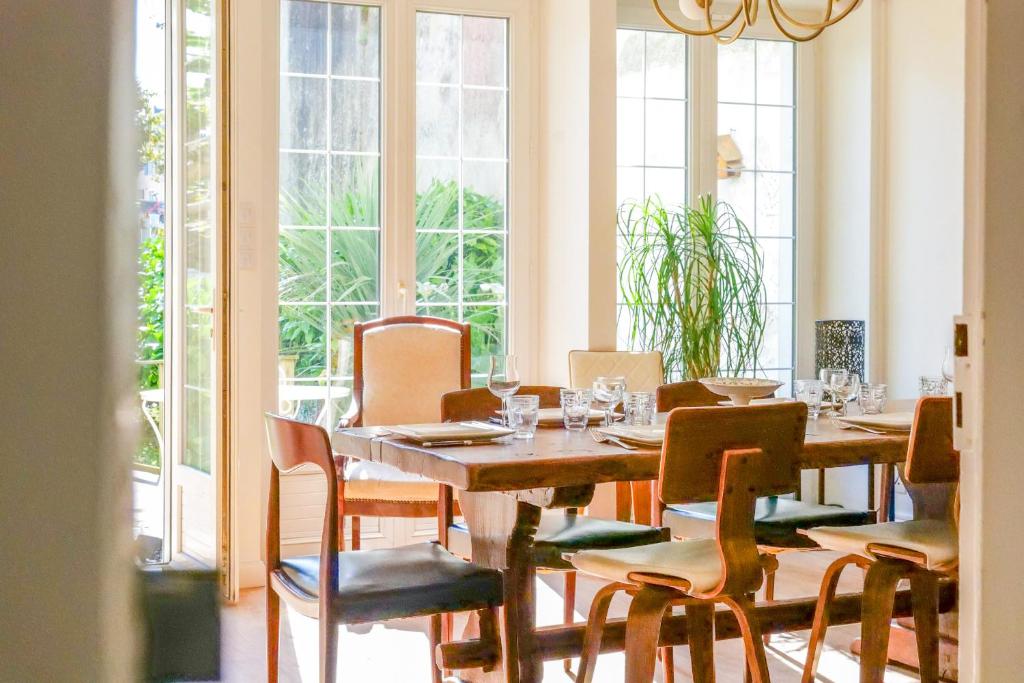 ein Esszimmer mit Tisch und Stühlen und Fenstern in der Unterkunft Maison bourgeoise - centre ville - 7 personnes in Les Sables-dʼOlonne