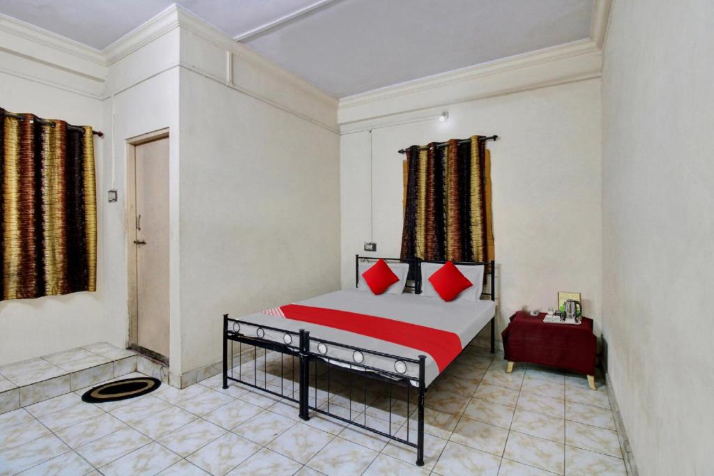 a bedroom with a bed with red pillows at Hotel O Kr Inn in Chandrapur