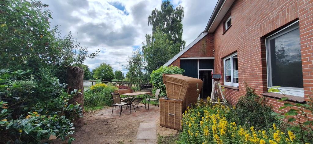 a garden with a table and chairs and a brick building at Ferienwohnung Eulennest, 35230 in Schwerinsdorf