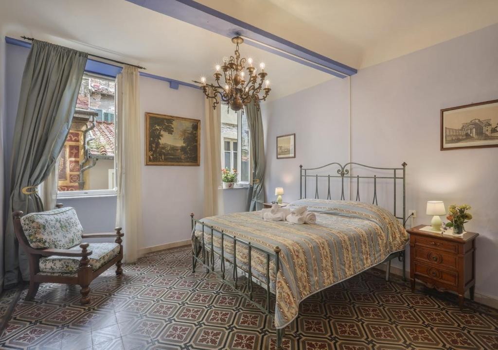 a bedroom with a bed and a chair and a chandelier at Fantastico Appartamento Lucca Centro Storico in Lucca