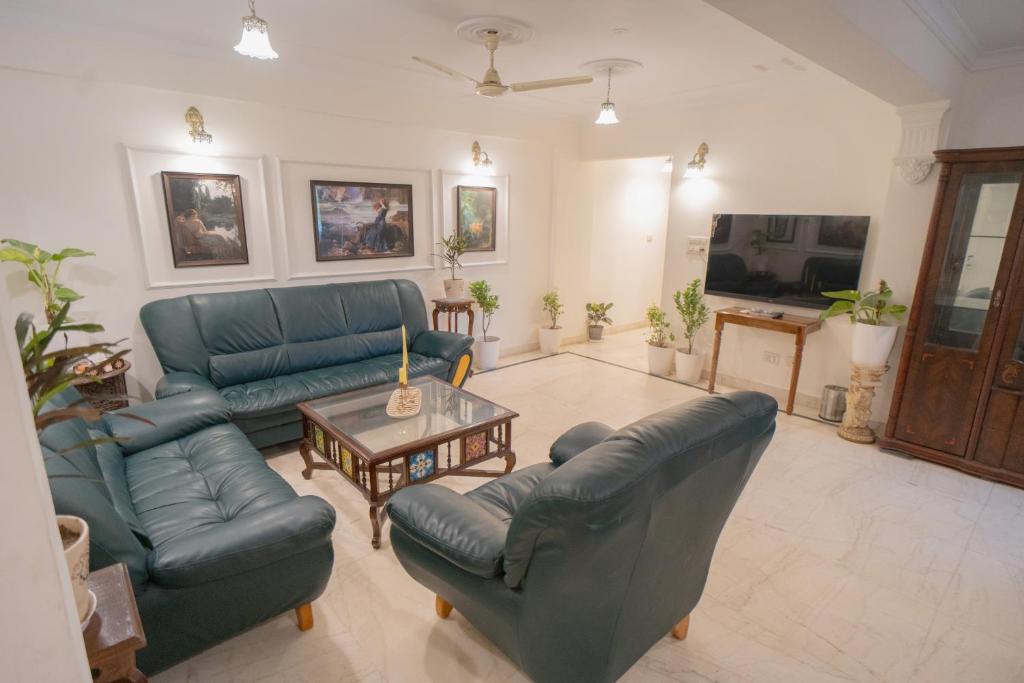 a living room with couches and a table and a tv at Kutani Stays - Civil Lines in Jaipur