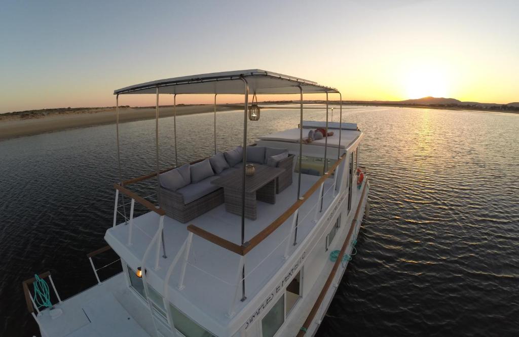 un barco con asientos en el agua al atardecer en Barco Casa Fuzeta, en Fuseta