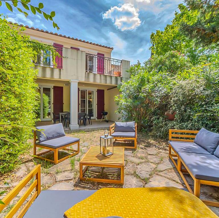 une terrasse avec des chaises et des tables en face d'une maison dans l'établissement Maison avec terrasse, jardin à 20mn Montpellier, à Saint-Clément-de-Rivière