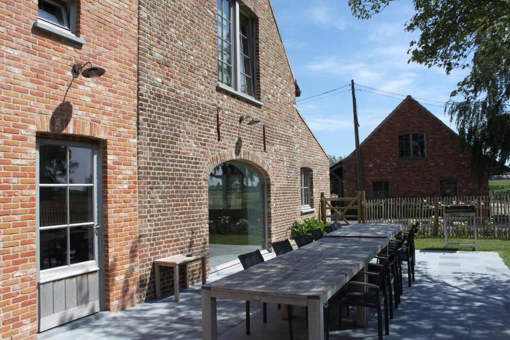 een lange houten tafel voor een bakstenen gebouw bij De Landweg in Tielt