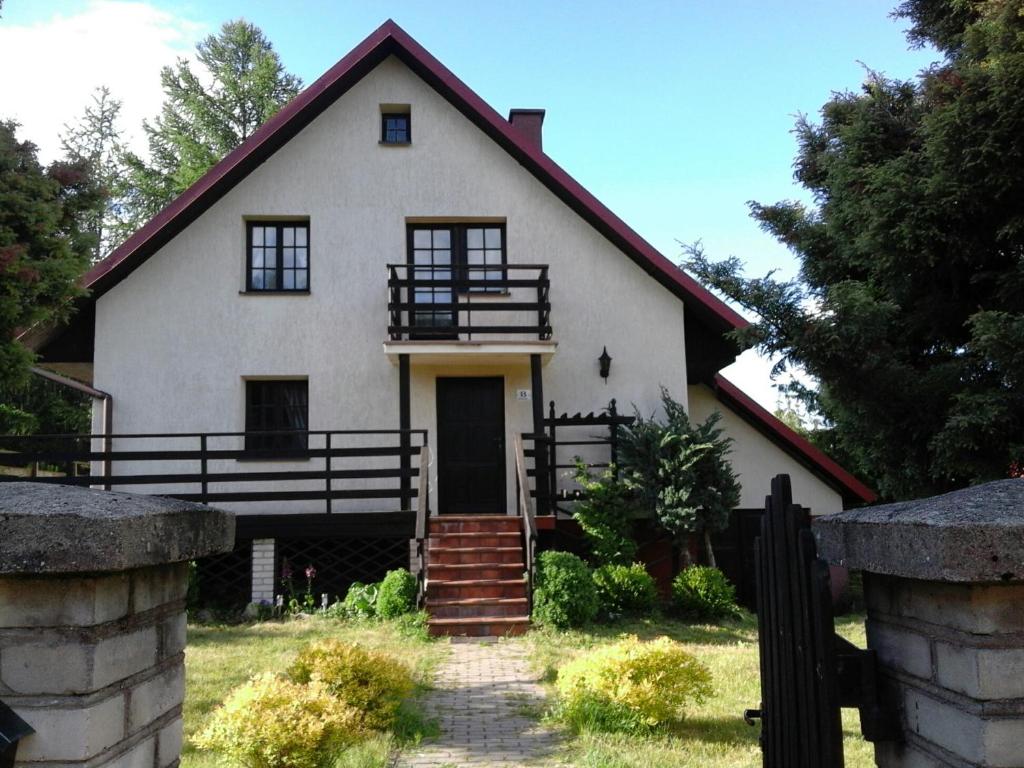 une maison blanche avec une porte en face dans l'établissement Wałpusz Holiday Home, à Szczytno