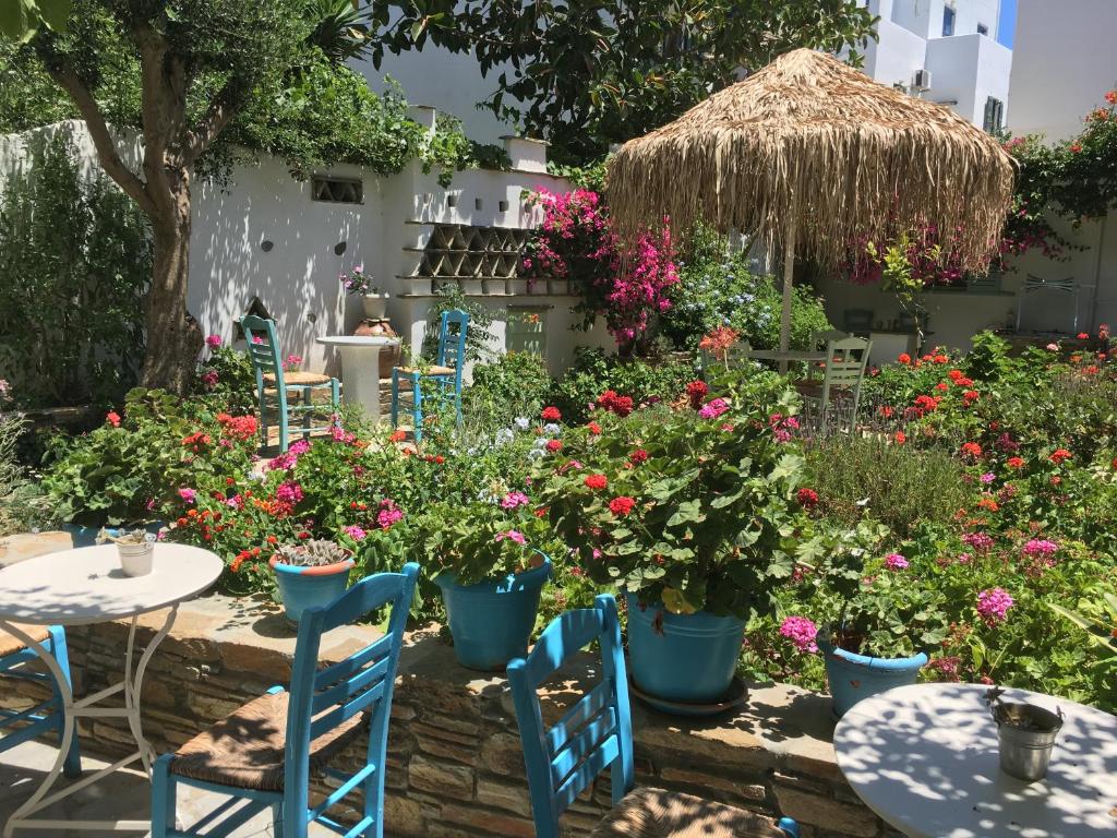 un jardín con mesas, sillas y flores en Nikoleta Rooms, en Tinos