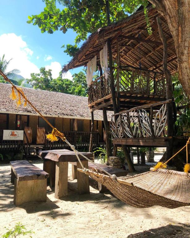 a hammock and a building with a tree at Amami Beachfront Bungalows & Villa in Puerto Galera