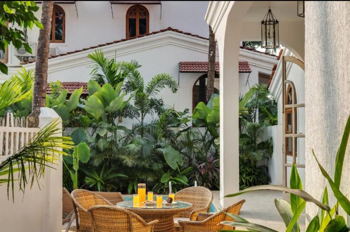 Un patio con una mesa y sillas frente a una casa. en Luxury 3Bhk Villa near Vagator, Goa, en Anjuna