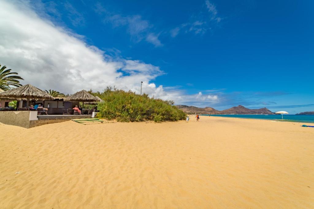 a sandy beach with umbrellas and the ocean at Hotel Porto Santo & Spa in Porto Santo