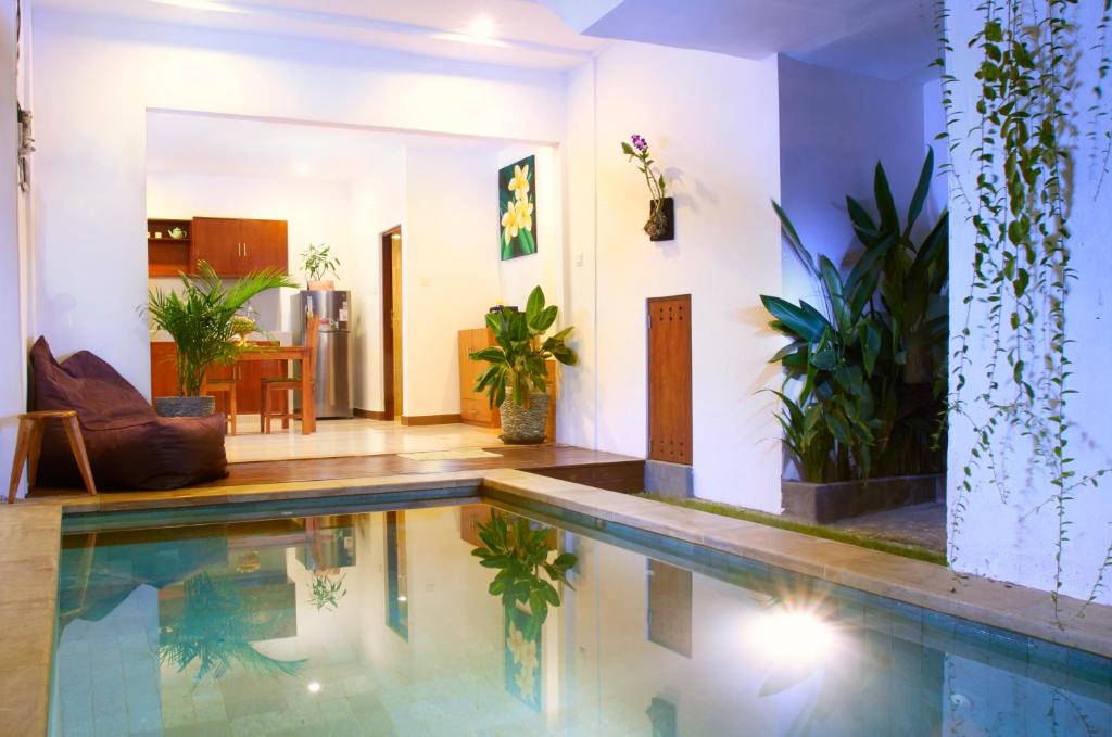 uma piscina numa sala de estar com plantas em Villa Sammy em Seminyak