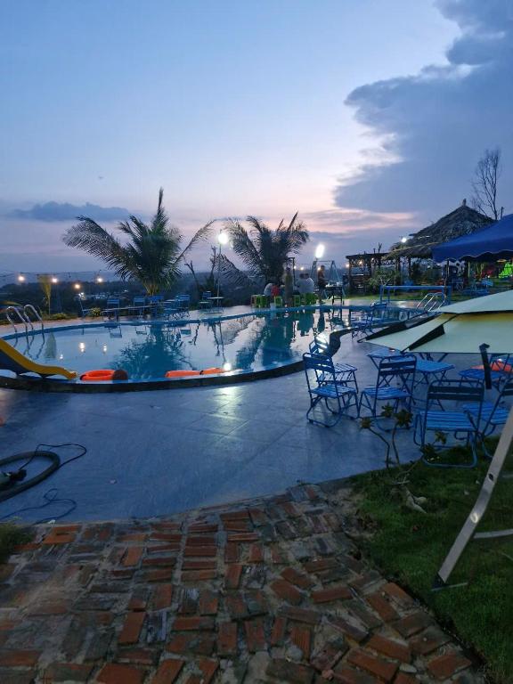 a large swimming pool with tables and chairs at a resort at SORA HOME STAY Ke Ga in Láng Văn Kê