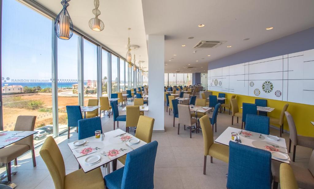 a restaurant with tables and chairs and large windows at Nicholas Color Hotel in Ayia Napa