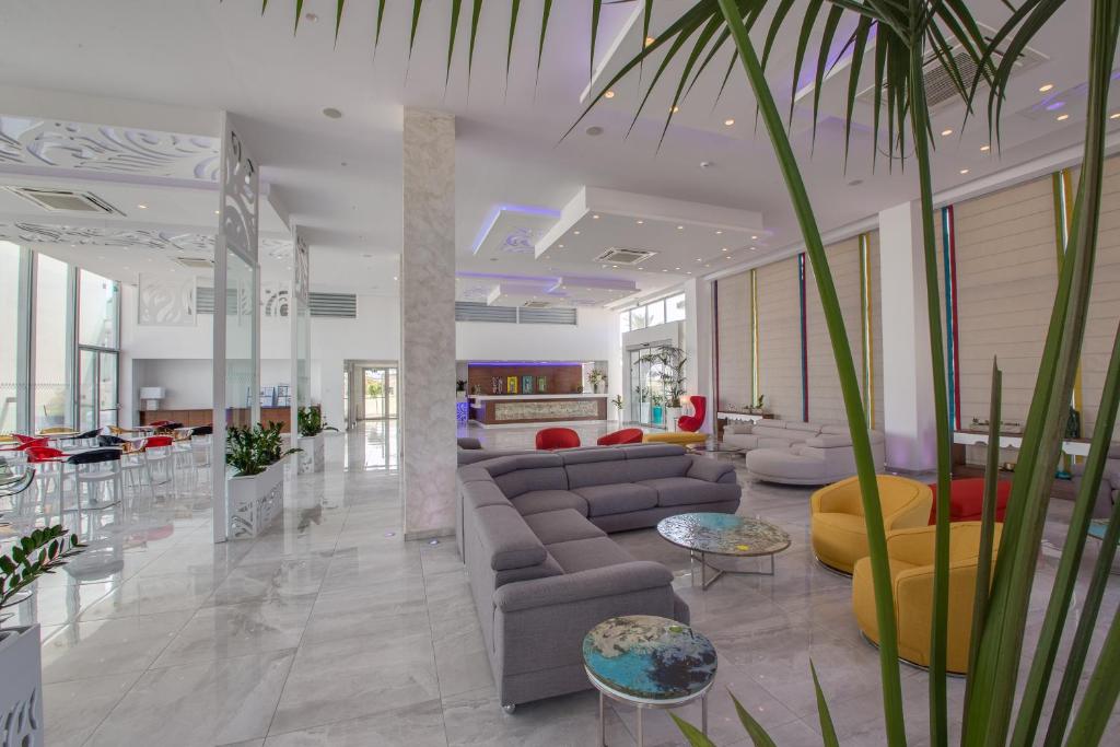 a lobby with couches and tables and a palm tree at Nicholas Color Hotel in Ayia Napa