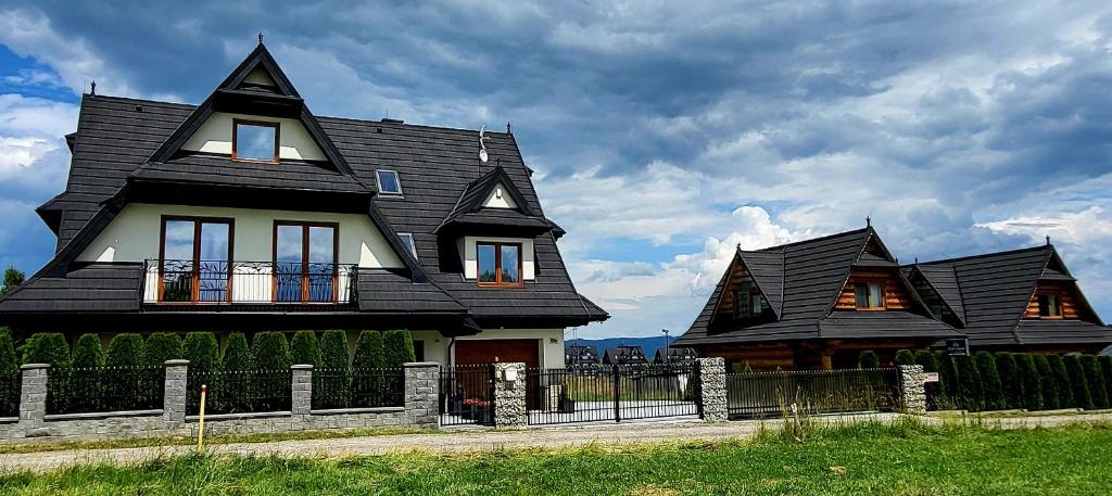 a large black and white house with a fence at Domki Białka & Apartamenty in Białka Tatrzanska