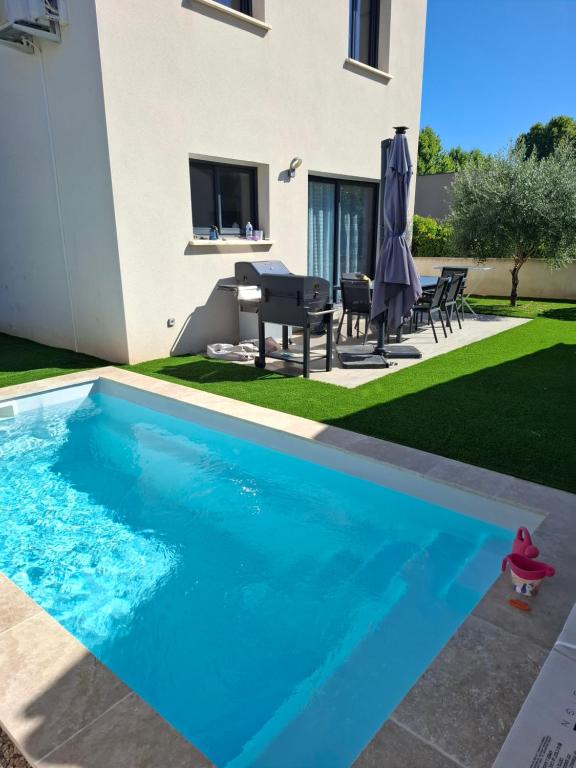 une piscine dans l'arrière-cour d'une maison dans l'établissement Charmante maison au cœur de Valergues avec piscine, à Valergues