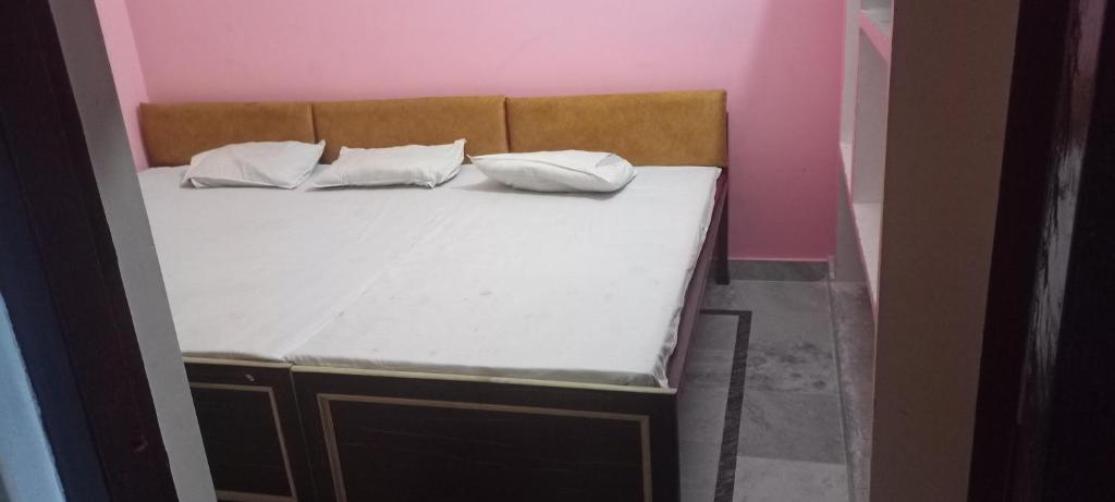 a bed in a pink room with two pillows on it at Shri Bhagwan Paying Guest House in Varanasi