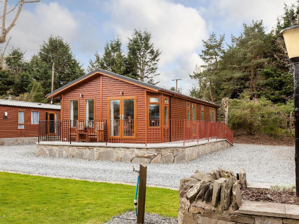 Cabaña de madera con porche y valla en Thistle Lodge, en Auchterarder