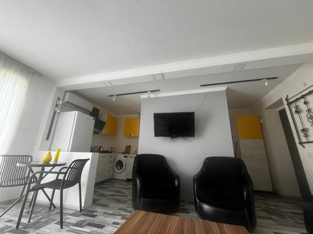 Una sala de estar con una mesa y sillas y un televisor. en Nina Home, 